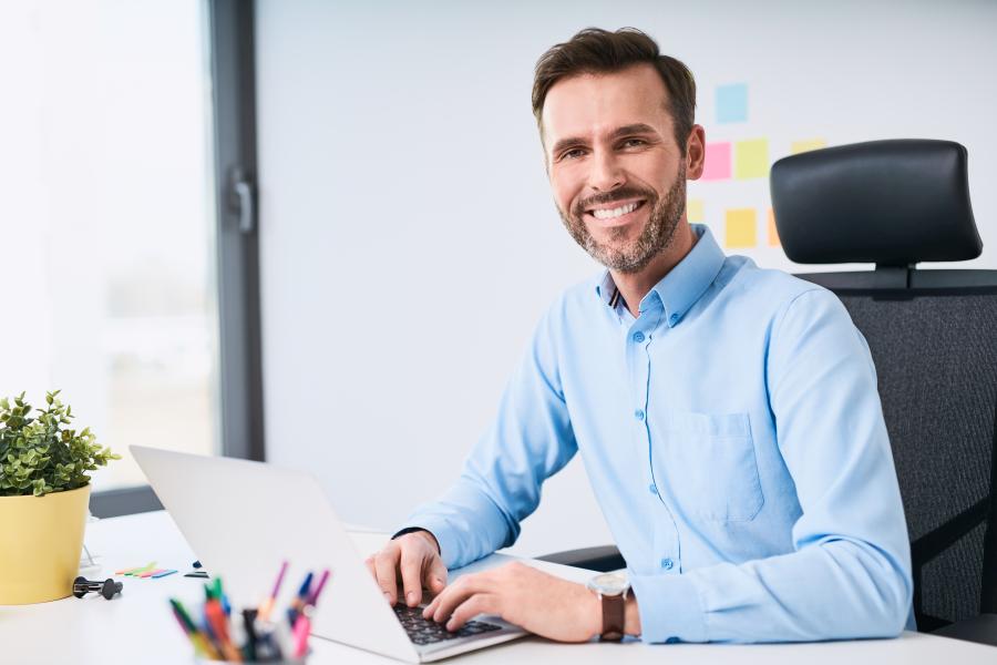Portrait of handsome businessman working on laptop at modern office